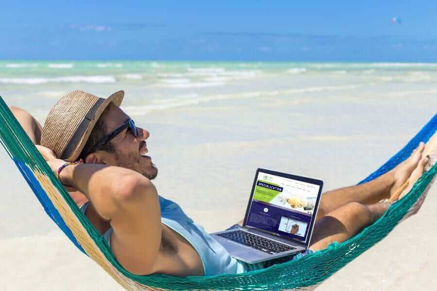 man doing work on laptop on the beach