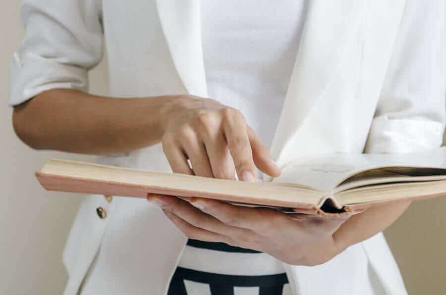 Woman flipping through book pointing at text