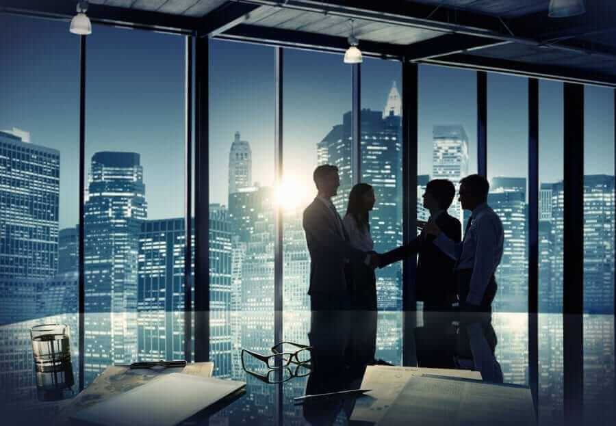 Business people silhouettes at office at night with dark cityscape in background