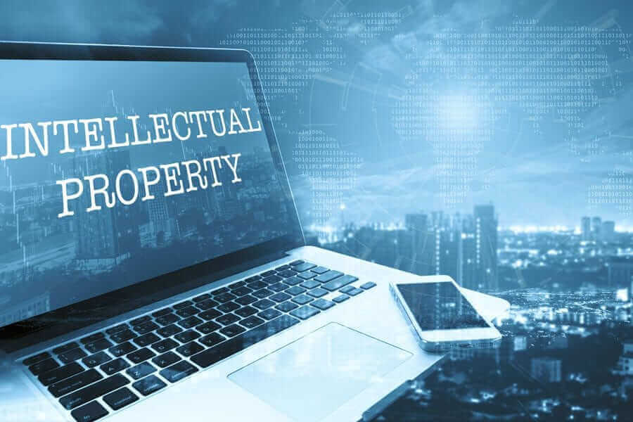 Laptop with text that says "Intellectual Property" over cityscape