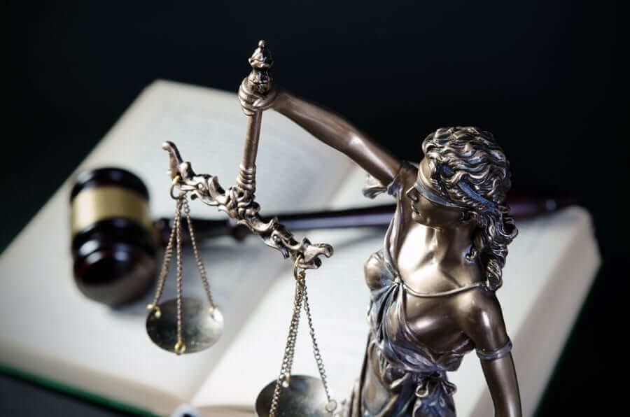 Lady Justice statue over gavel and open book