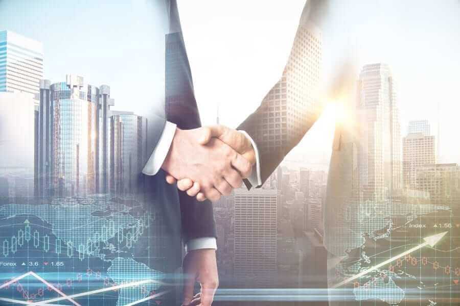 Two businessmen shaking hands overlayed over city