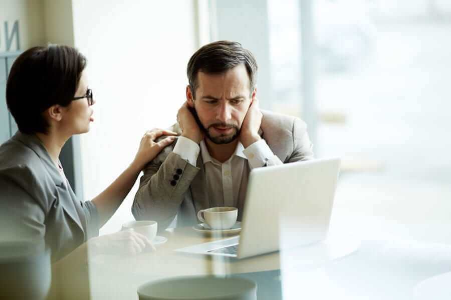 Man looking at computer stressed with woman talking to him