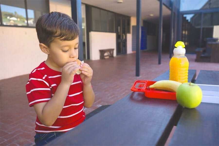 Boy eating sandwich outside of school