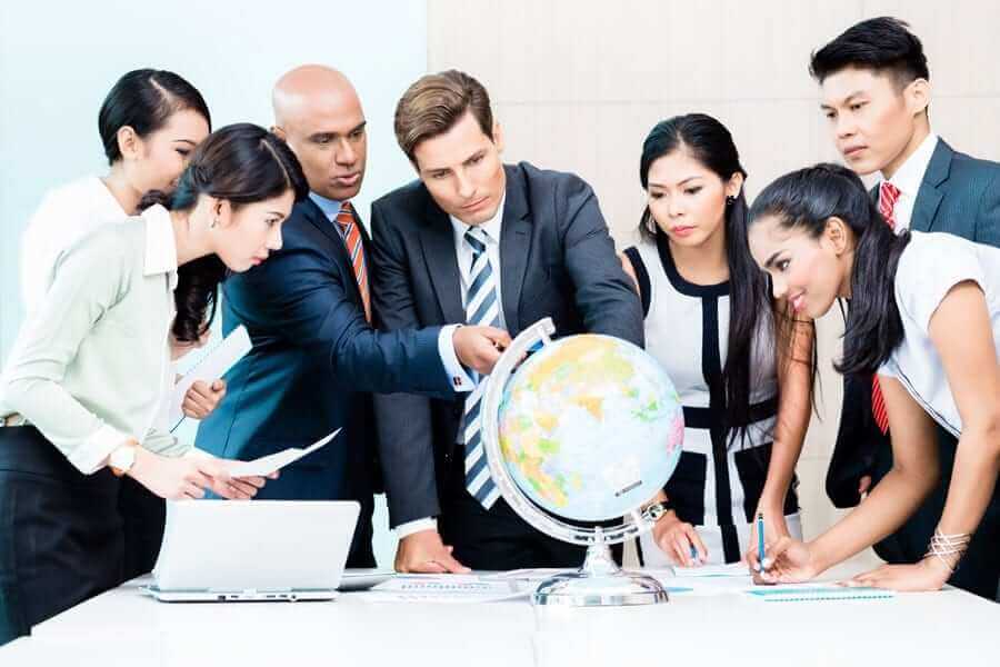 Multiple Business People surrounding and pointing at globe