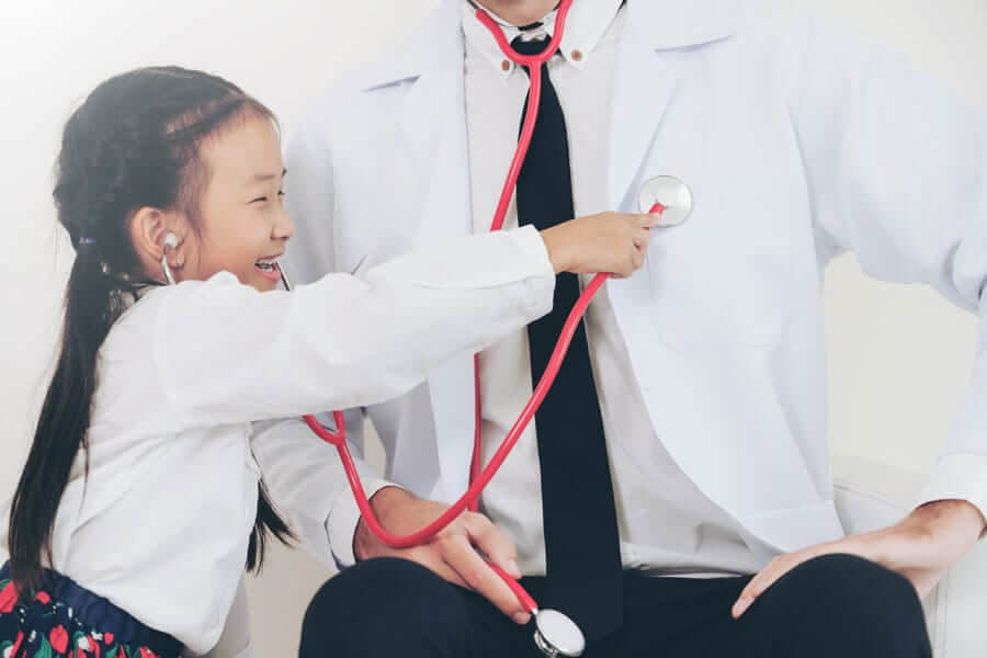 young girl using stethoscope on doctor