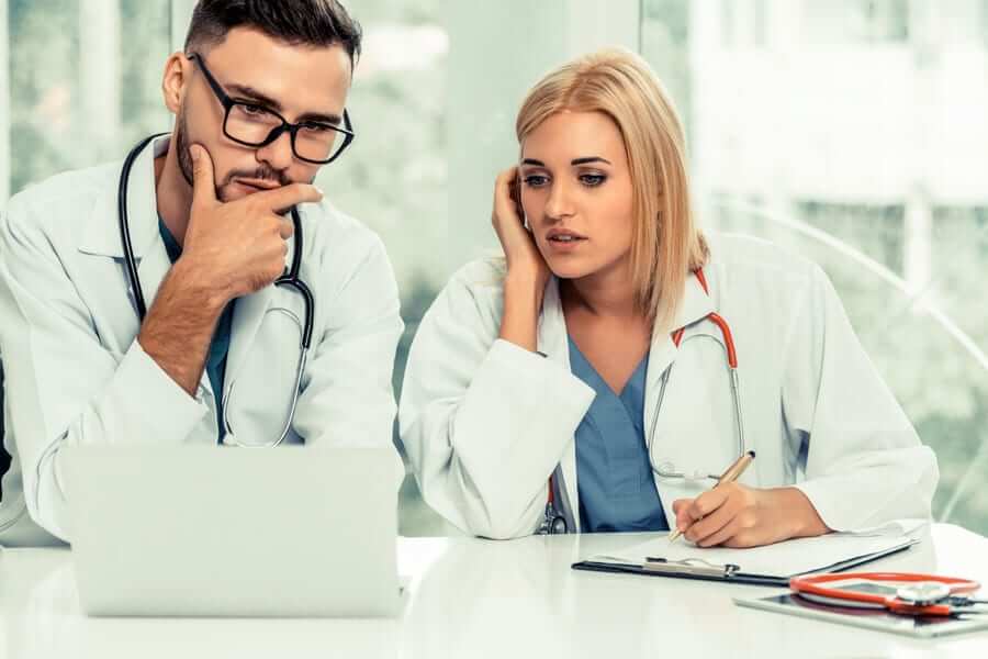 male and female doctor looking at laptop screen perplexed