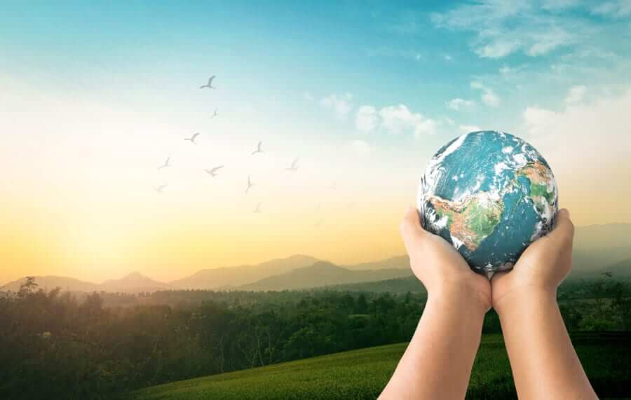 Hands holding up planet earth with landscape background